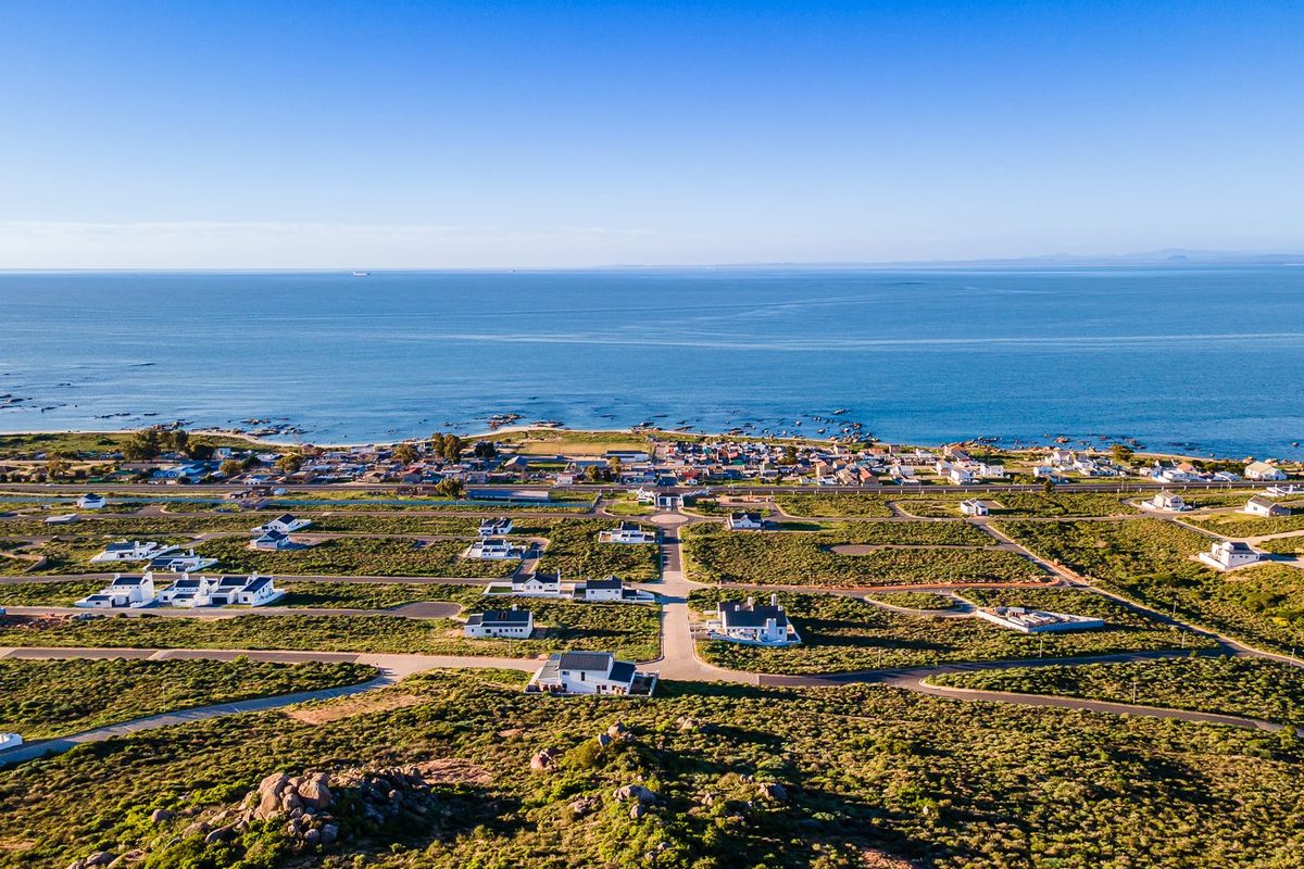 An aerial view of a coastal residential development featuring established road infrastructure and proximity to the ocean.