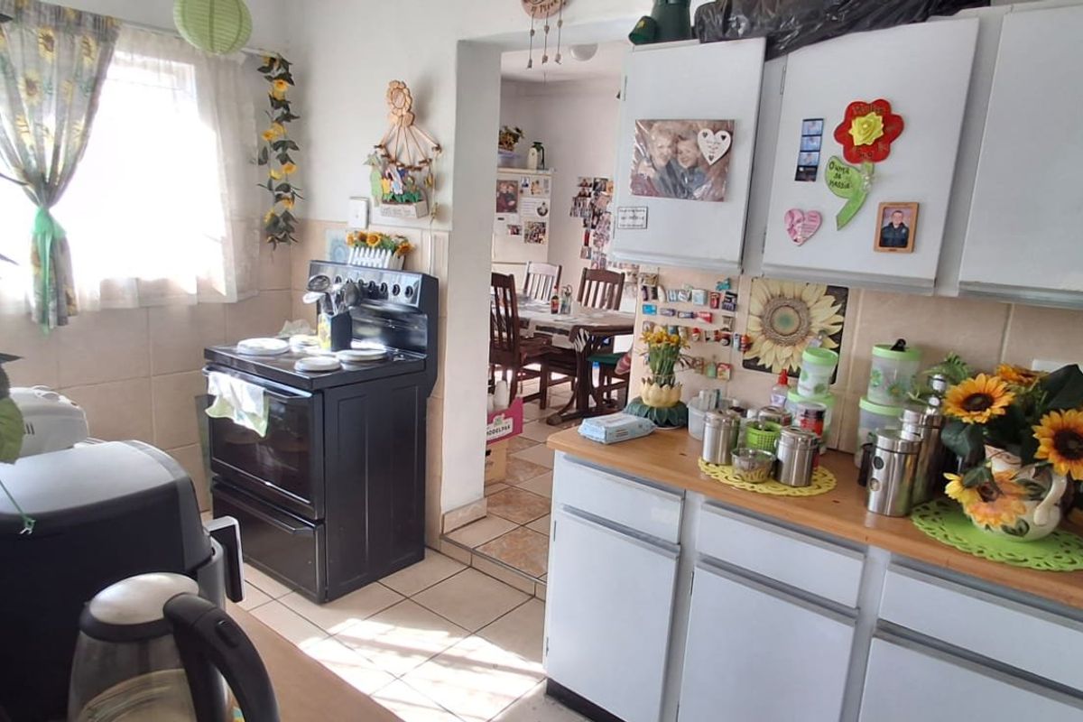 A functional kitchen featuring tiled flooring, a tiled backsplash, and built-in cabinetry, with an open-plan flow leading into the adjacent dining area.