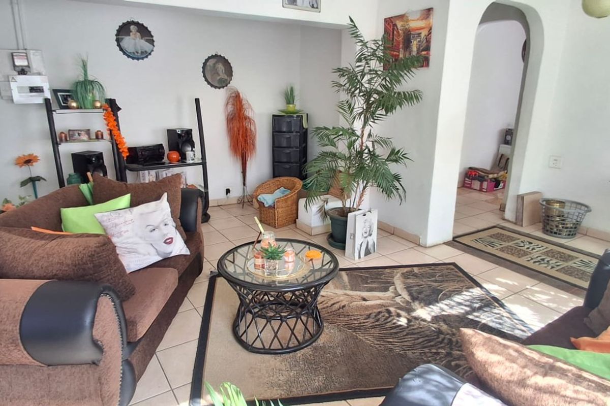 A living room area featuring tiled flooring and an arched doorway leading to an adjacent space.