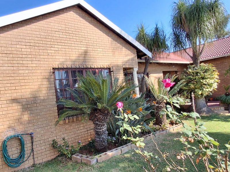 A view of the rear face brick facade of the house, featuring a well-maintained garden and established landscaping.