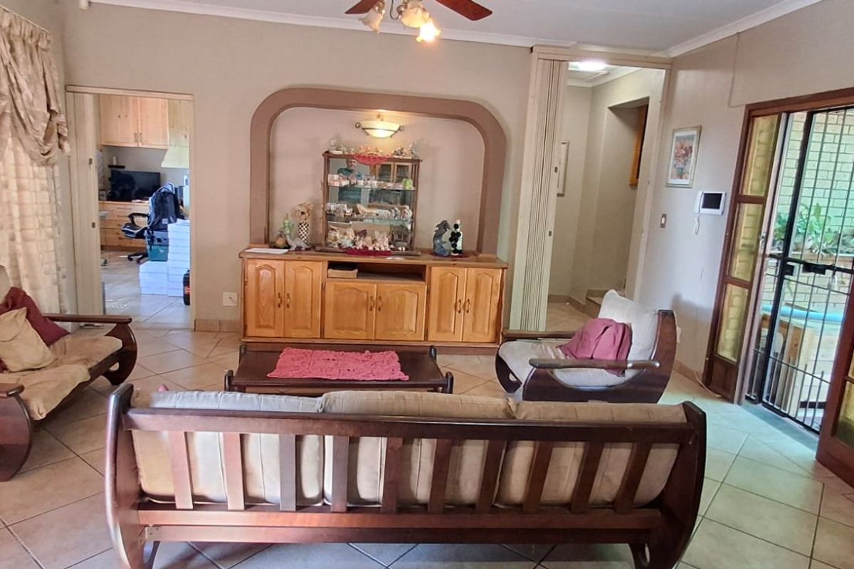 A spacious living room featuring ceramic tile flooring, a built-in arched display niche, and access to the exterior via wooden-framed french doors.