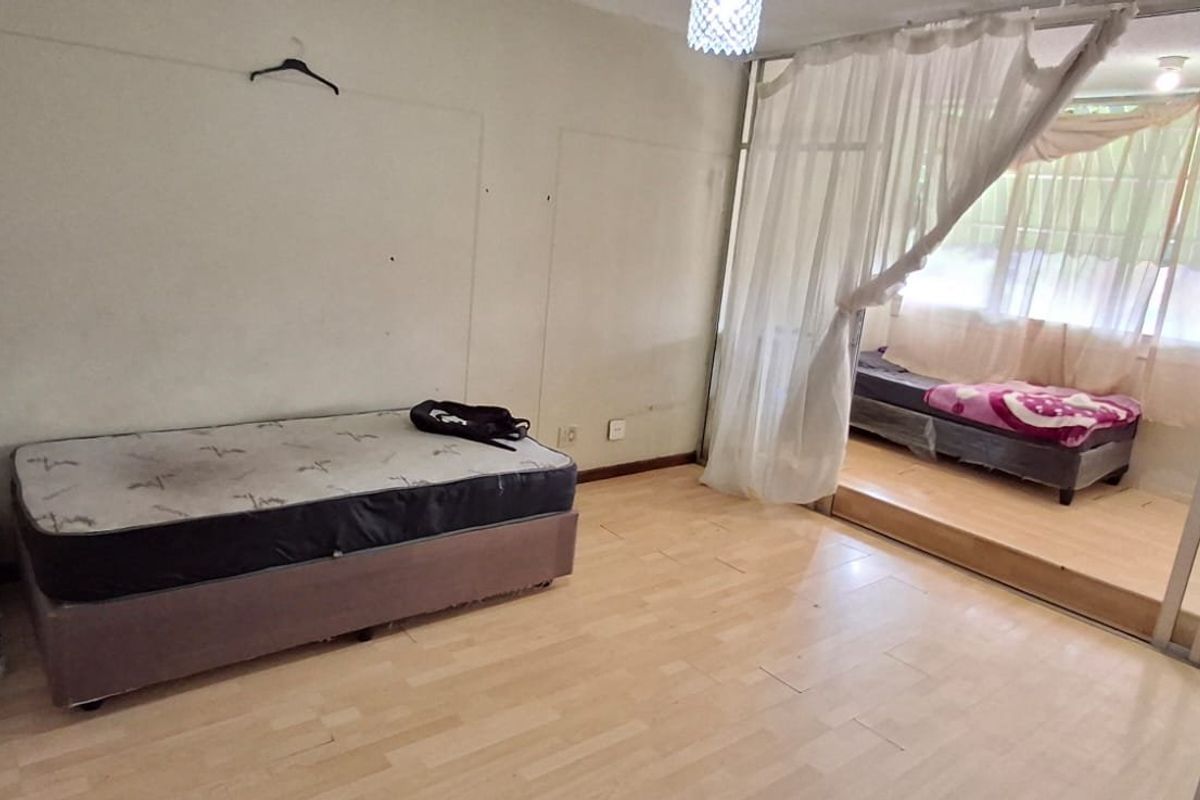 Bedroom featuring laminate flooring and a raised platform area separated by a sliding glass partition, offering potential for a functional living space.