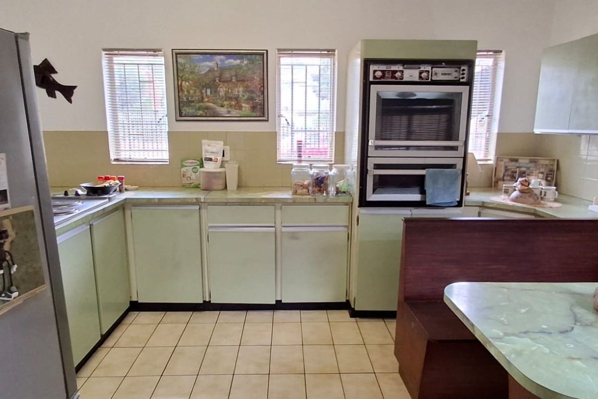 A dated kitchen featuring original cabinetry, tiled backsplash, built-in double oven, and tiled flooring, offering significant potential for a modern renovation.