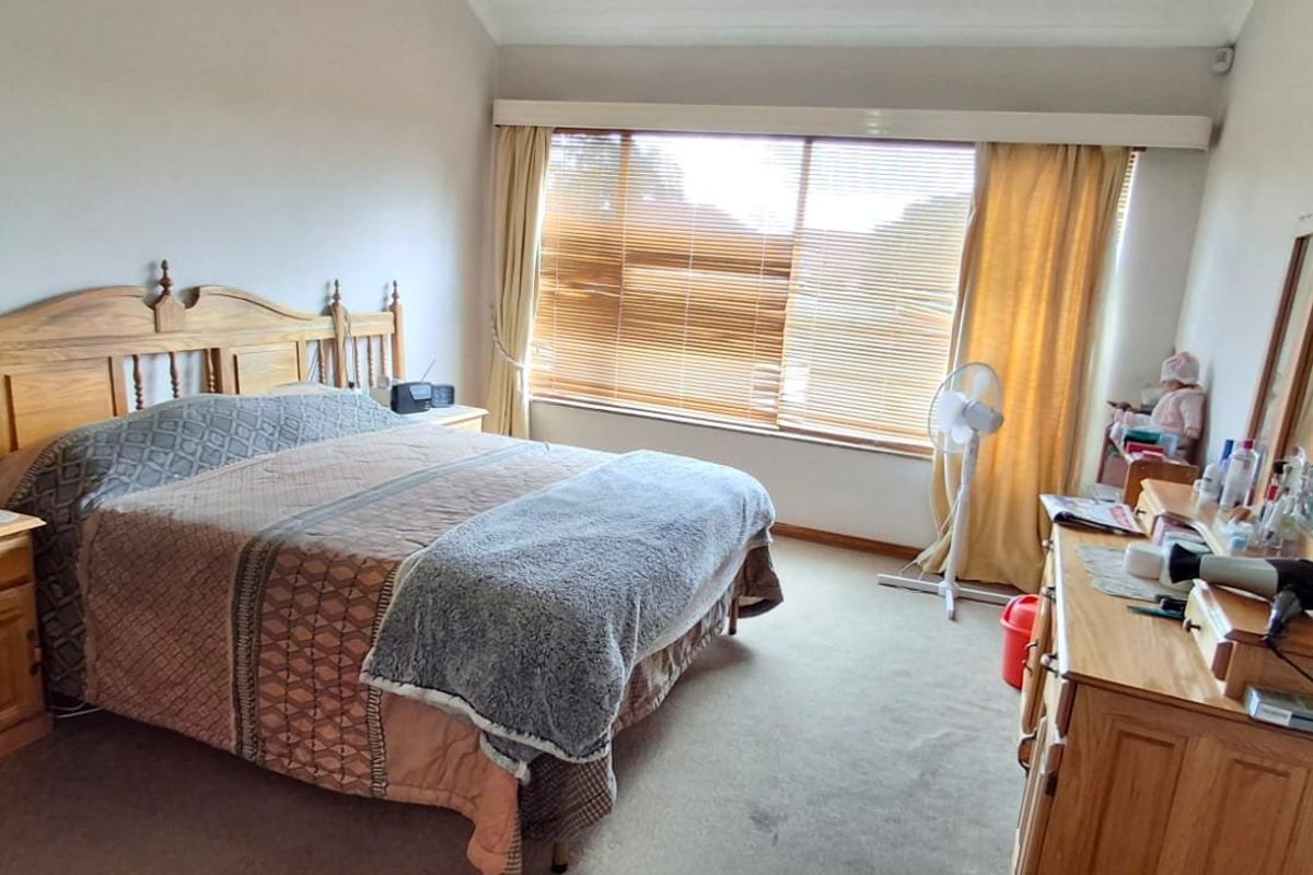 A spacious bedroom featuring carpeted flooring and large windows with fitted blinds, offering a functional layout ready for modern updates.