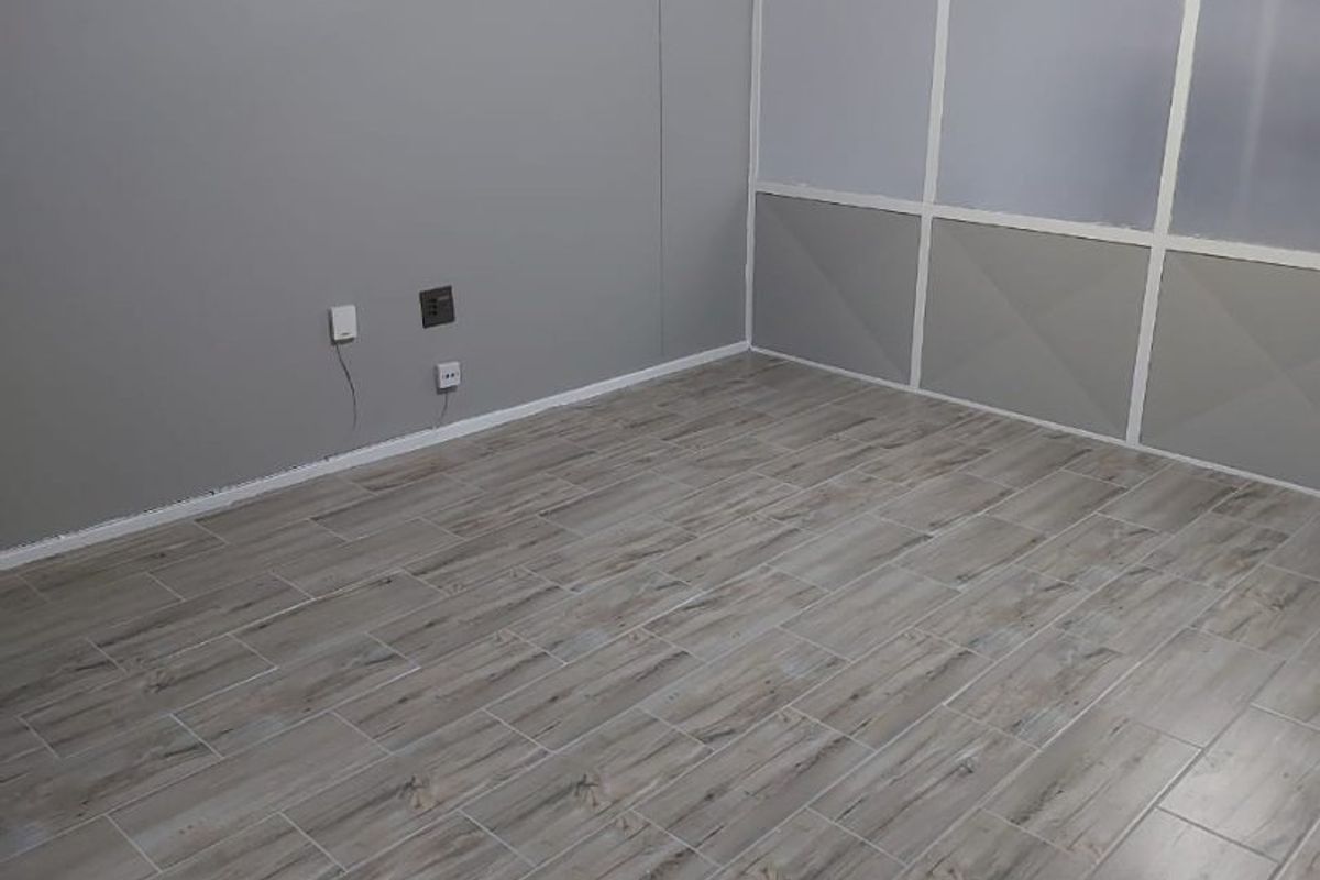 An empty room featuring wood-look tile flooring and a modern frosted glass partition wall, providing a clean and neutral space.