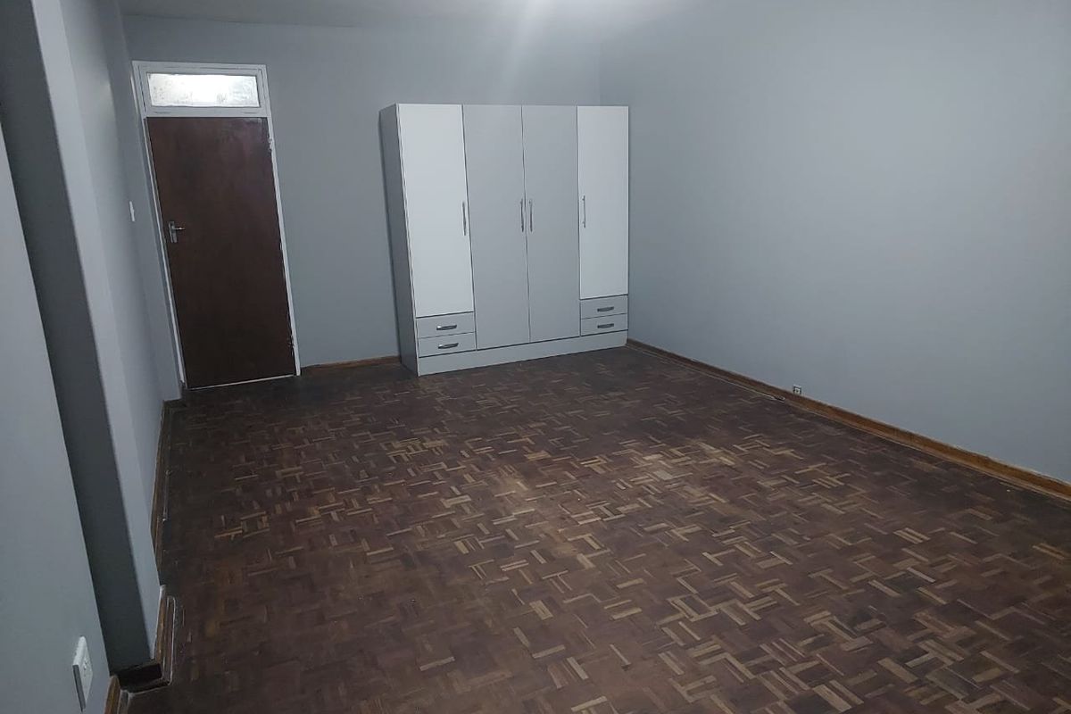 A spacious bedroom featuring classic parquet flooring and a built-in wardrobe, offering a neutral canvas ready for personalization.