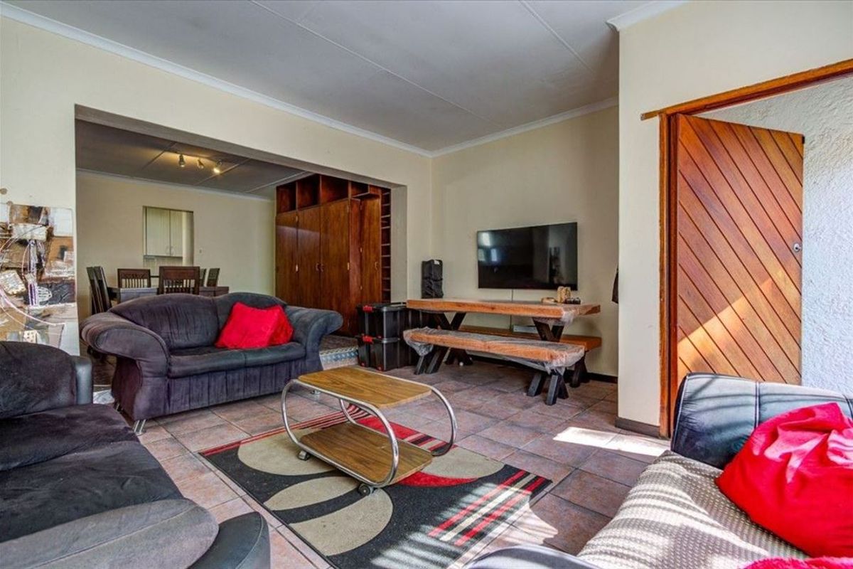Open plan living and dining area featuring tiled flooring and built-in wooden cabinetry, providing a functional and connected living space.