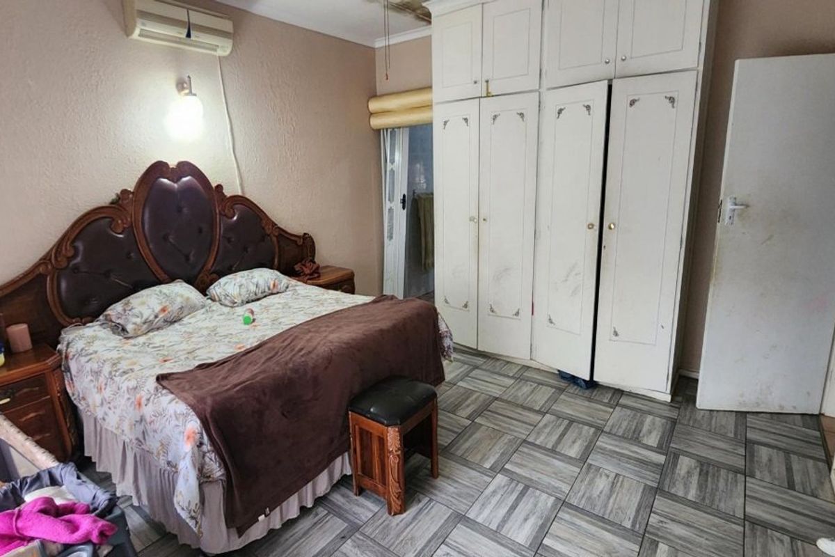 Bedroom featuring tiled flooring, built-in cupboards, and an air conditioning unit. The space offers functional storage and climate control.