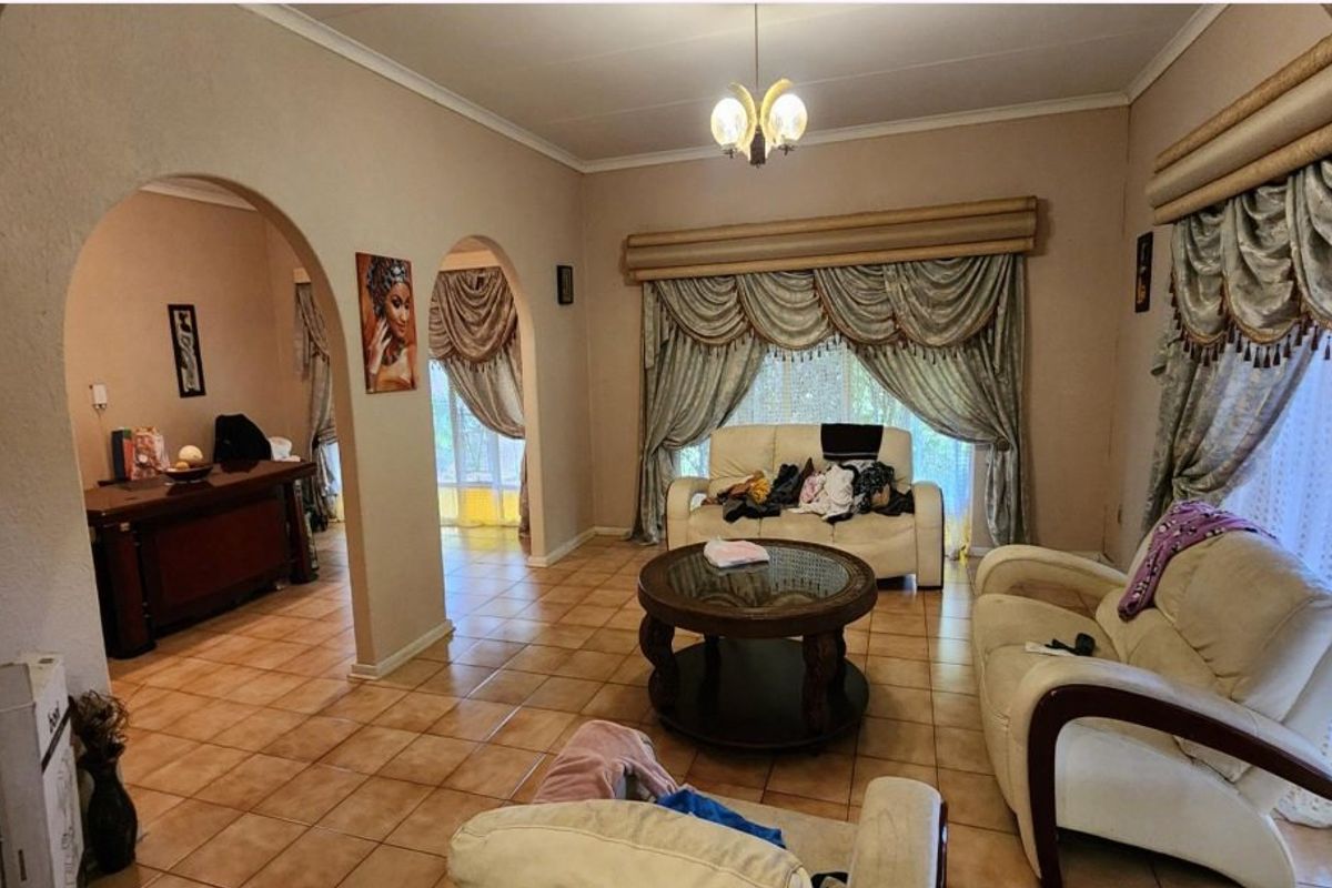 Spacious living room featuring ceramic tile flooring, distinctive arched architectural details, and coved ceilings, offering a traditional layout with multiple connected living areas.