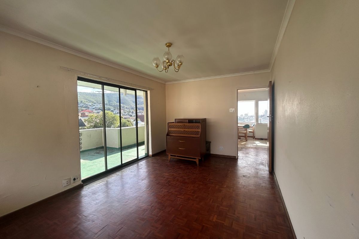 Spacious living area featuring original parquet flooring, coved ceilings, and large sliding glass doors providing access to an outdoor balcony.