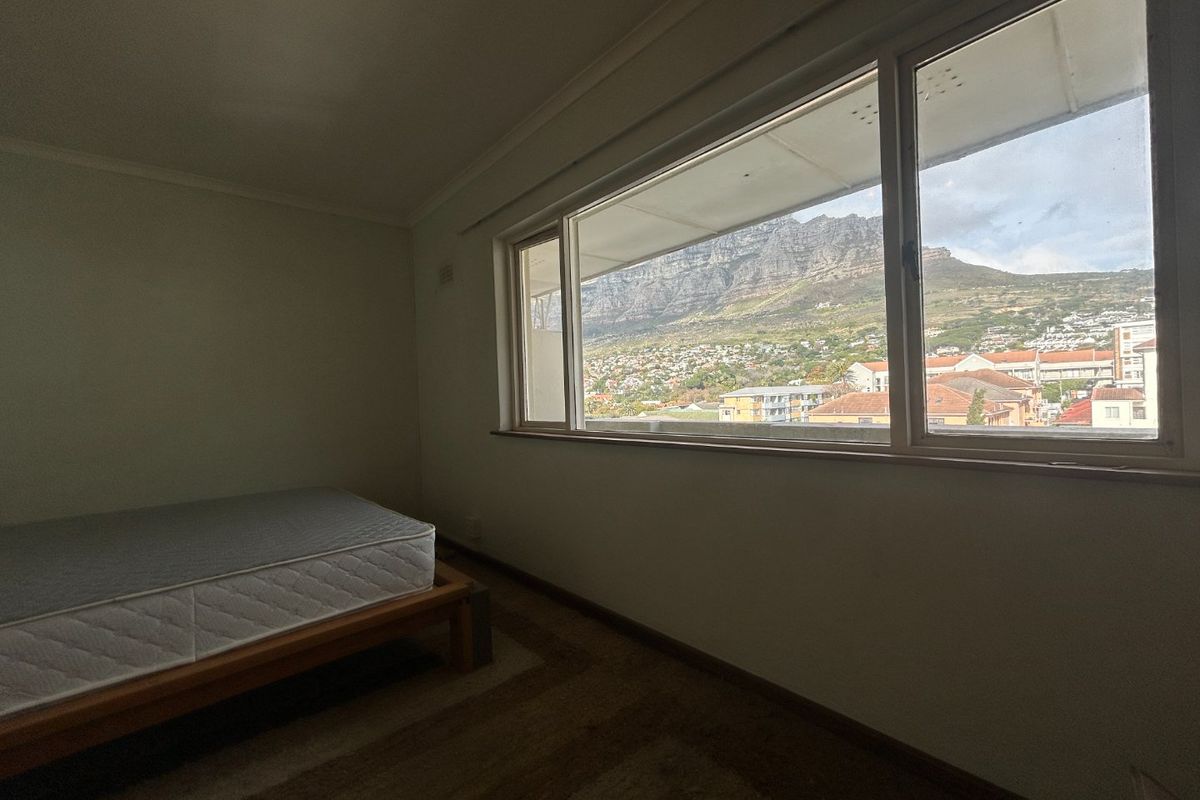 A spacious, empty bedroom featuring a large window that offers a clear, scenic view of the mountain.
