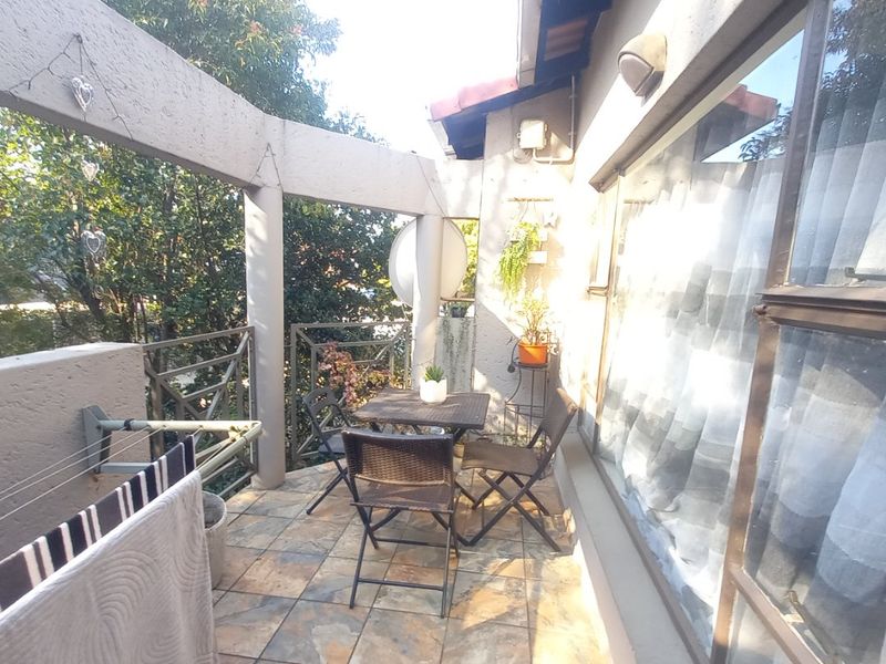 A covered balcony featuring tiled flooring, a metal balustrade, and a wall-mounted drying rack, providing a functional outdoor space.