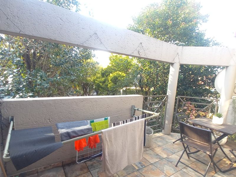 A private balcony featuring tiled flooring, a concrete balustrade, and structural support pillars, offering an outdoor space for relaxation.