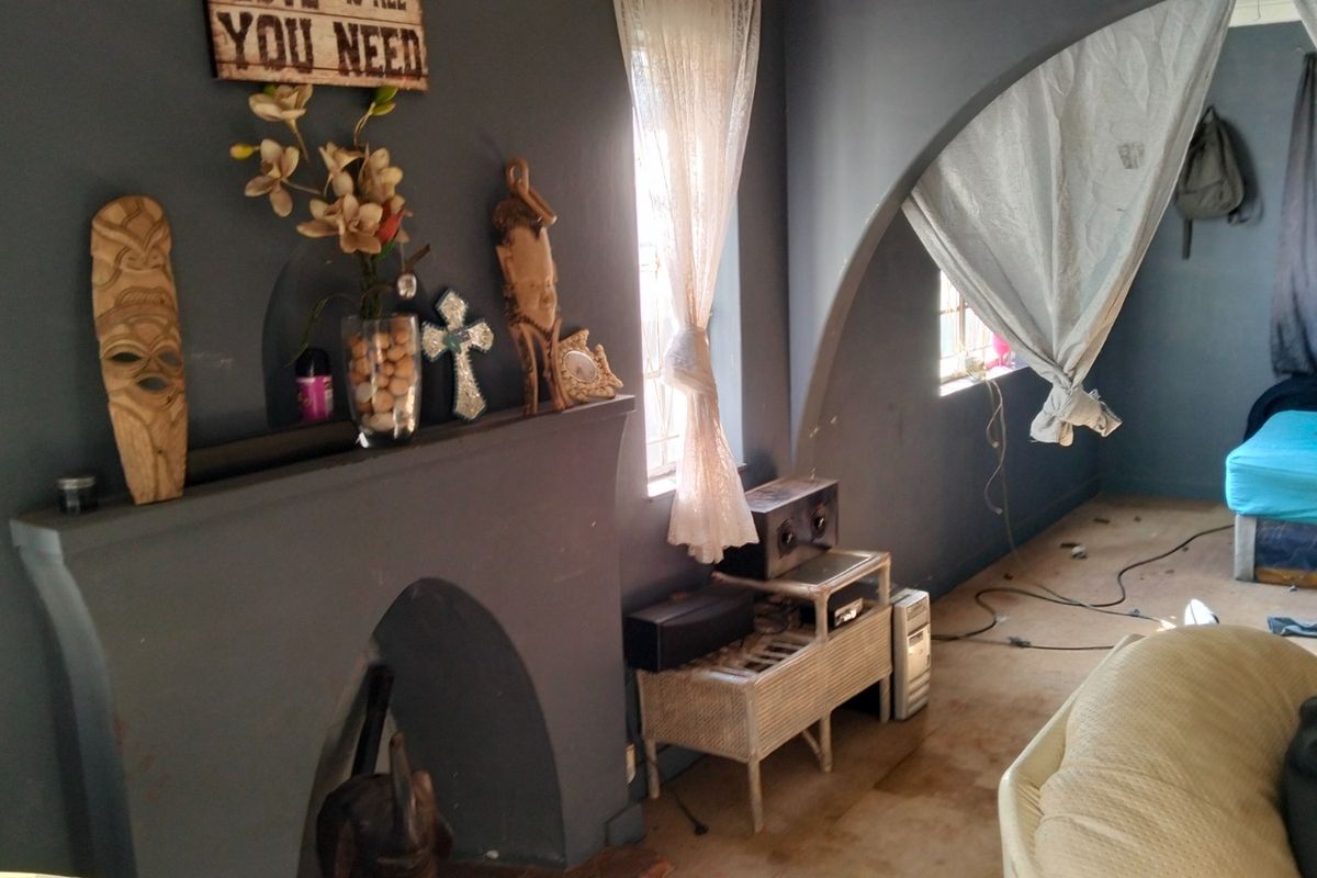 A living room featuring a dark-painted built-in fireplace and a distinctive arched architectural opening leading to an adjacent space.