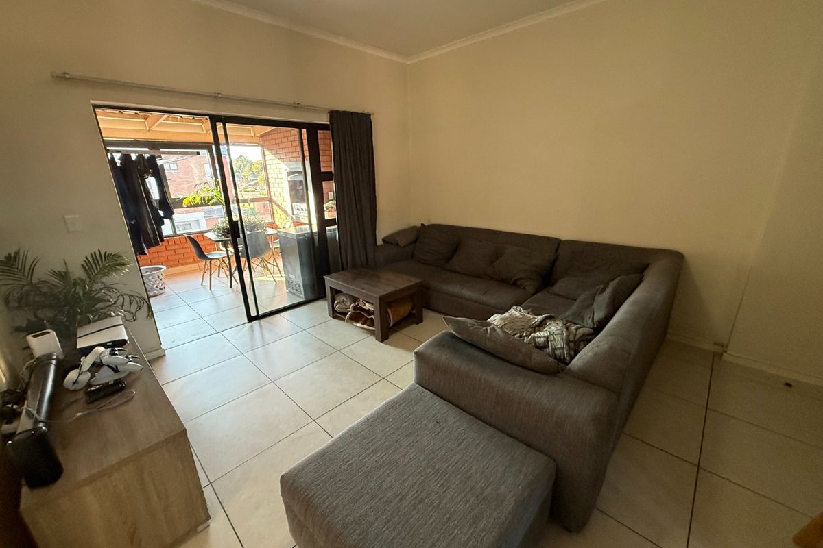 A living room featuring tiled flooring and a large sliding glass door providing access to an outdoor patio area.