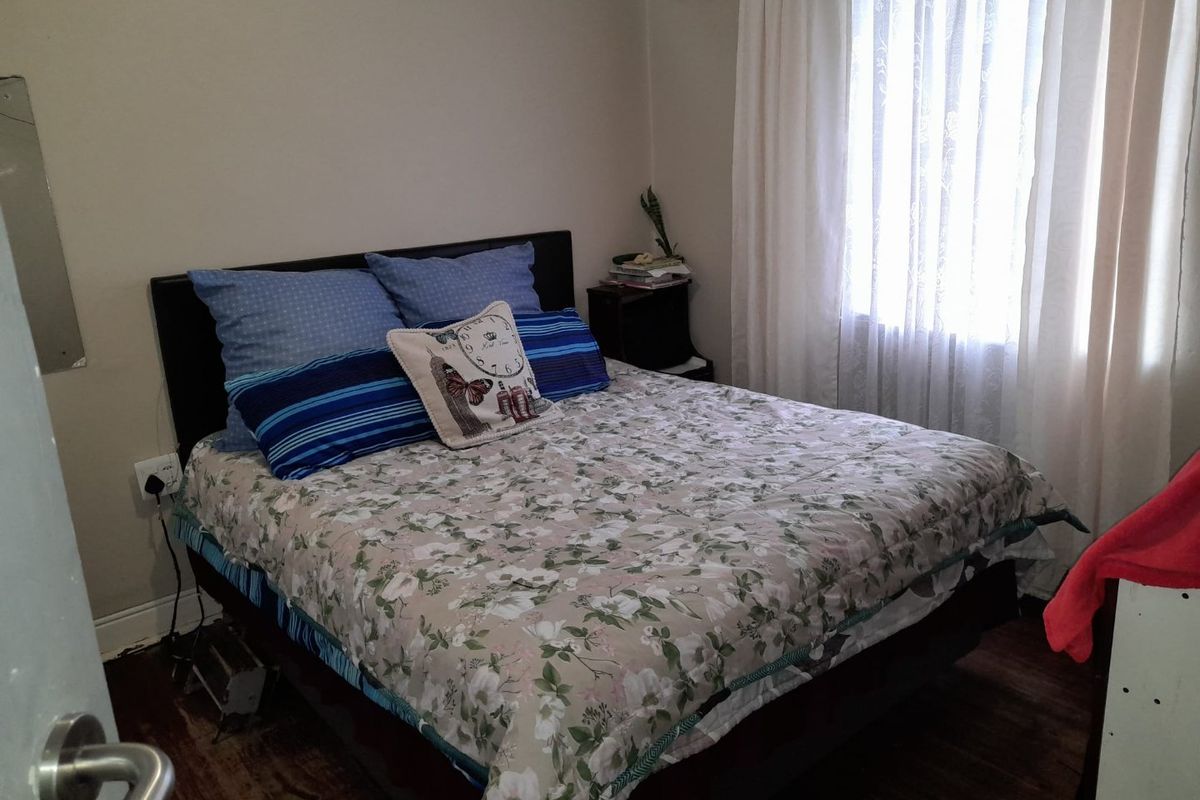 A standard bedroom featuring laminate flooring and window treatments, providing a functional space for rest.