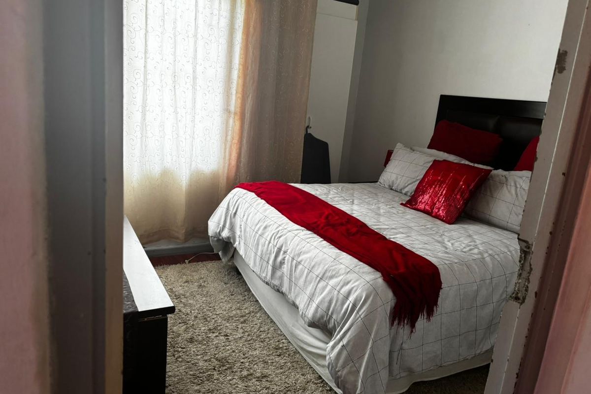 A standard bedroom featuring a built-in wardrobe and natural light from the window, with visible wear to the door frame.