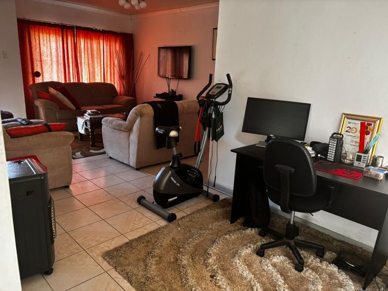 Open-plan living area featuring tiled flooring and a dedicated space for a home office setup.