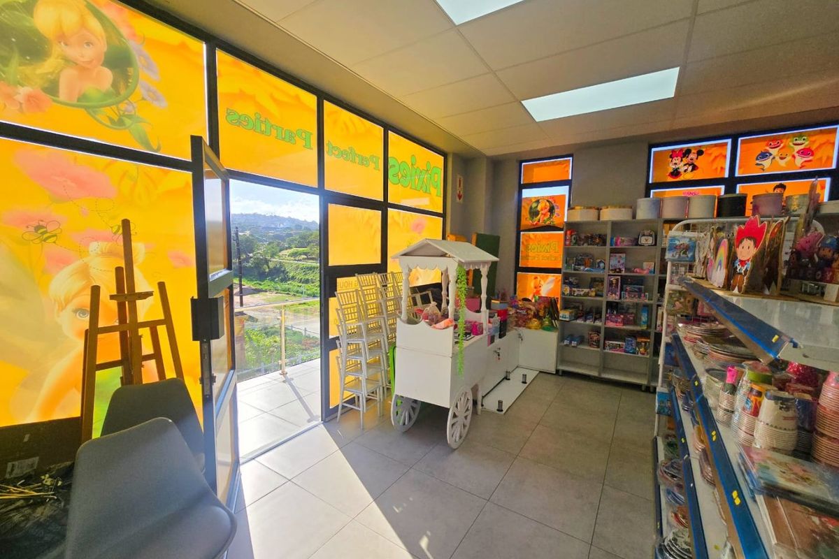 Commercial retail space featuring large glass windows, tiled flooring, and built-in shelving, suitable for a party supply or event planning business.