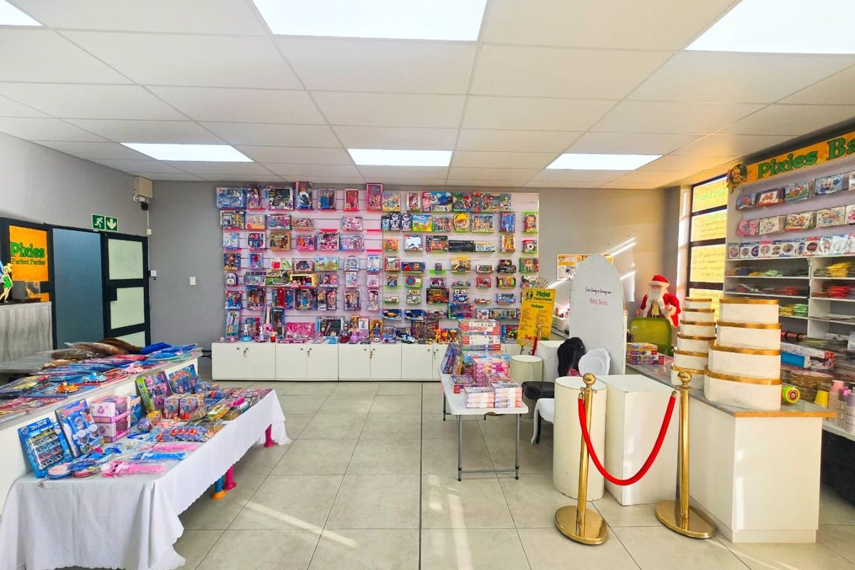Commercial retail space featuring tiled flooring, suspended ceiling with recessed lighting, and extensive wall-mounted display shelving with integrated base cabinetry.