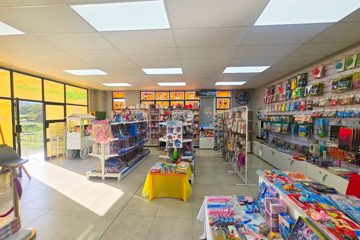 A well-lit commercial retail space featuring tiled flooring, suspended ceiling with recessed lighting, and extensive slatwall display systems for merchandise.
