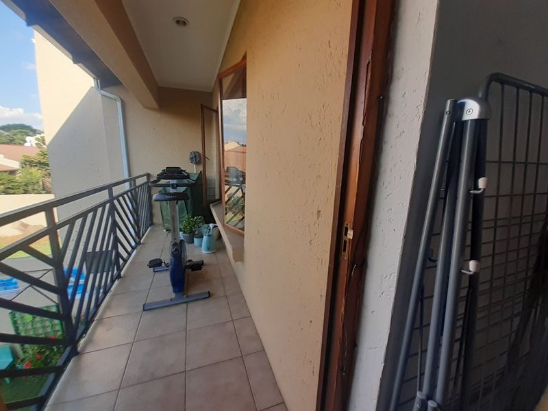 A covered balcony featuring tiled flooring and a metal balustrade, providing an outdoor space accessible from the interior.