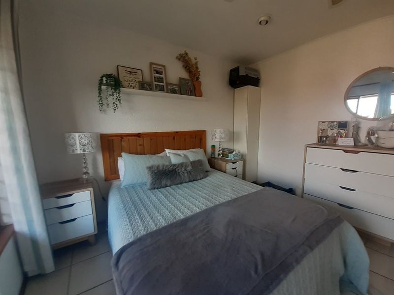 A functional bedroom featuring tiled flooring and a neutral wall finish, providing a comfortable and well-lit sleeping space.