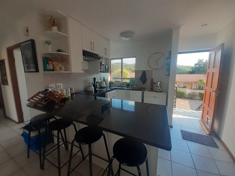Open plan kitchen featuring a granite breakfast bar, built-in cabinetry, and tiled flooring, with direct access to the exterior.