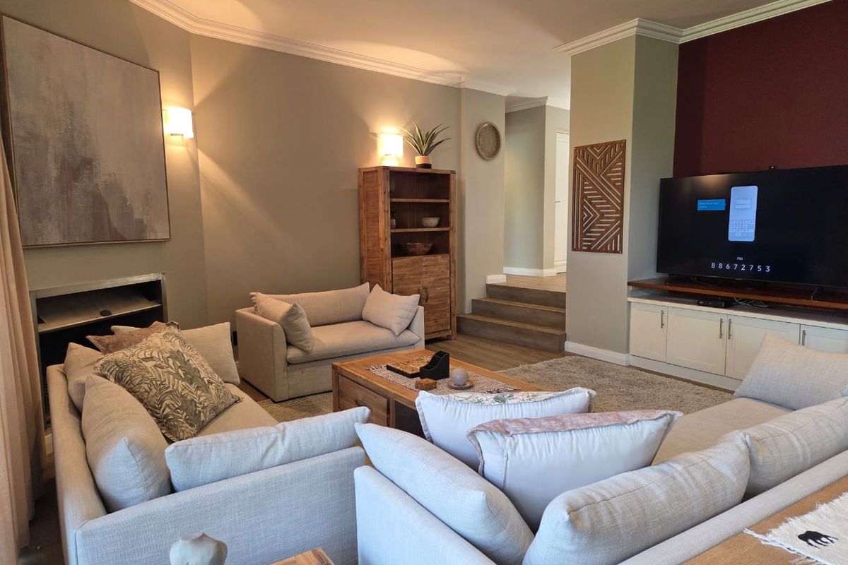 A well-maintained living room featuring built-in cabinetry, a fireplace, and elegant coving, with a split-level layout leading to an adjacent hallway.