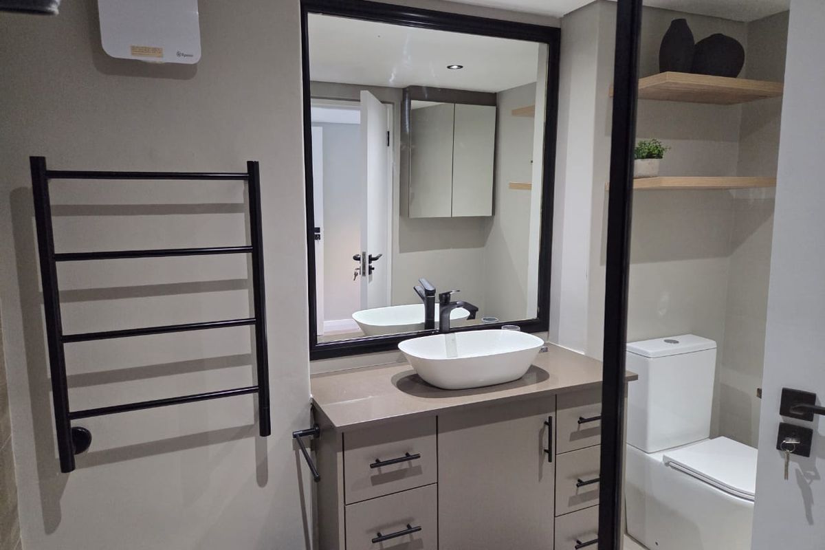 Modern bathroom featuring a vanity with vessel sink, black fixtures, heated towel rail, wall-mounted toilet, and floating timber shelves.