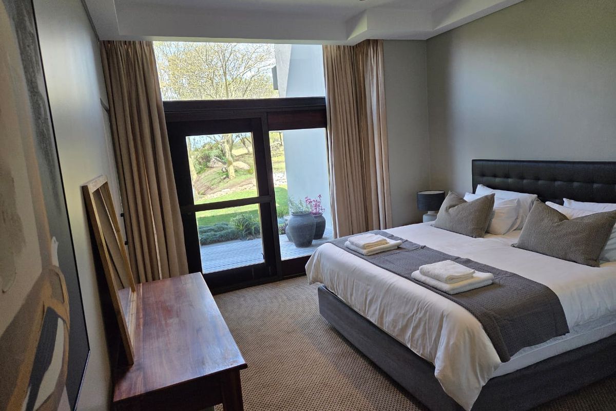 A well-maintained bedroom featuring recessed ceiling lighting, carpeted flooring, and a large sliding glass door providing direct access to an outdoor patio area.