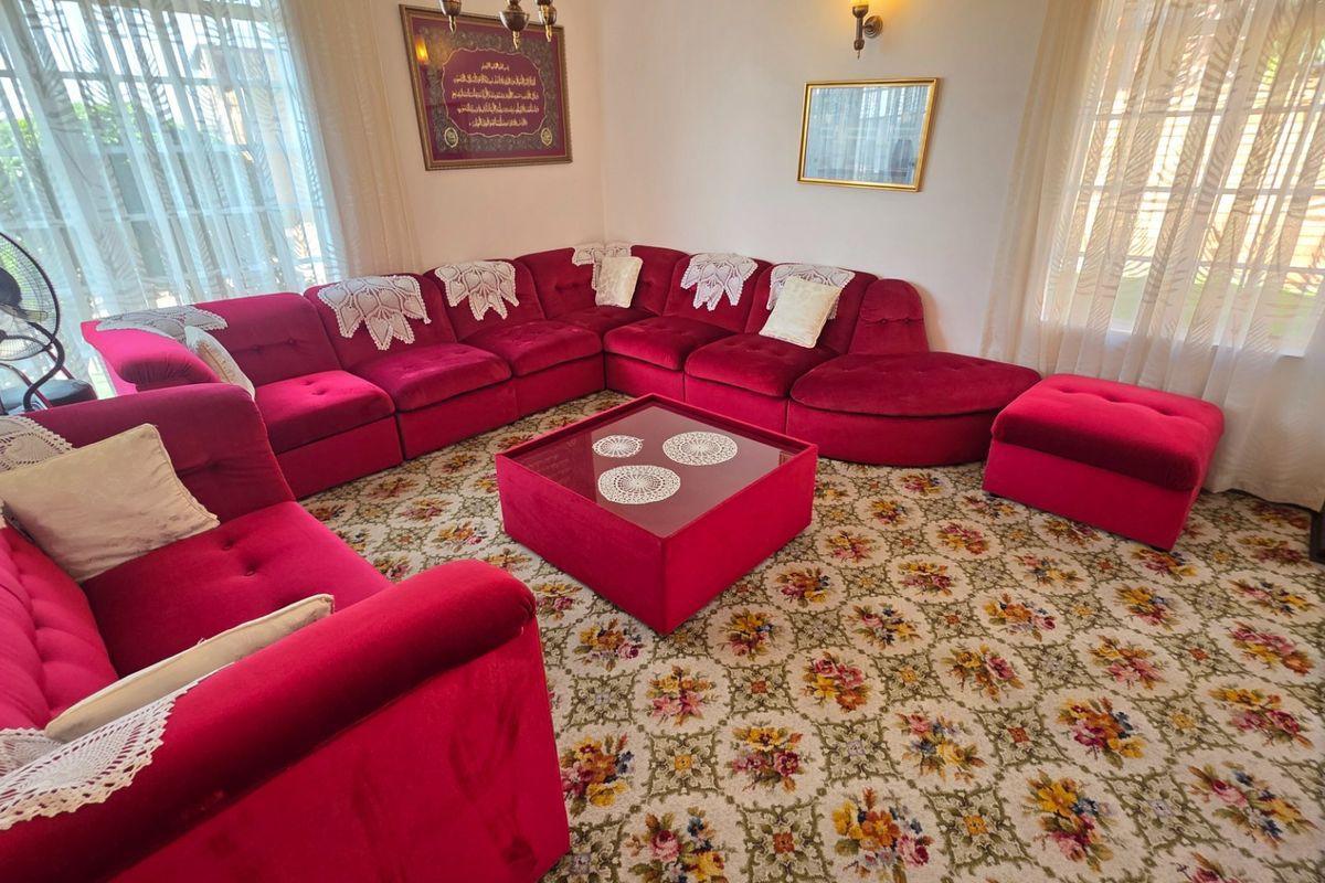 A living room featuring patterned carpeting, wall sconce lighting, and large windows with sliding glass door access to the exterior.