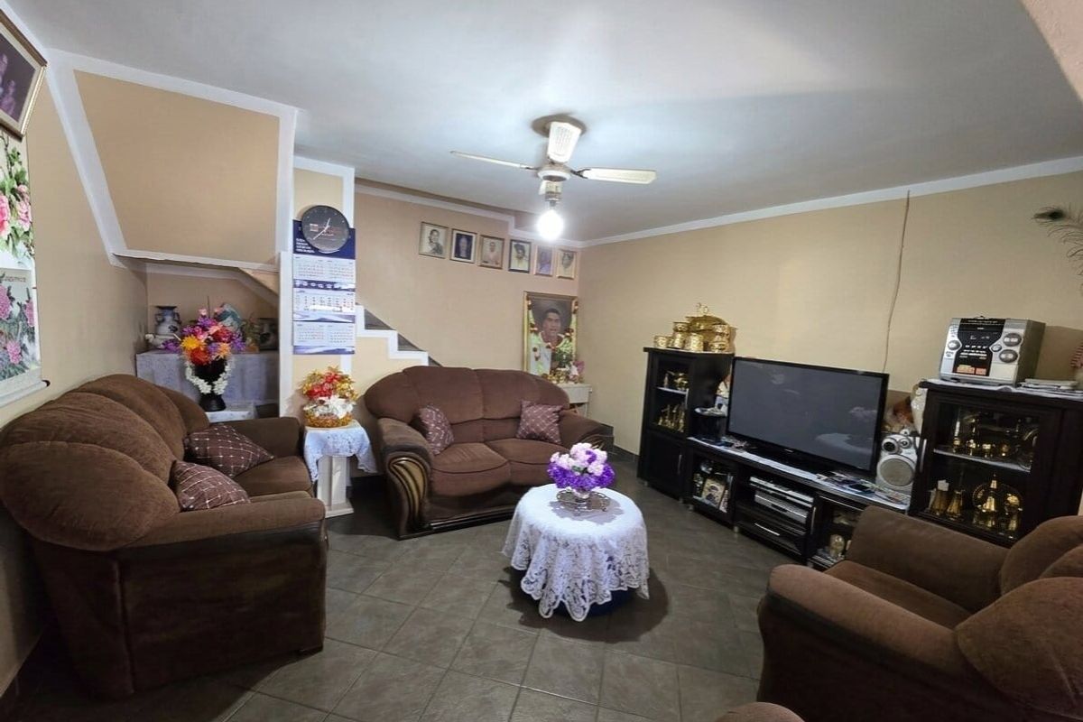 A living room featuring tiled flooring, a ceiling fan, and an integrated staircase, providing a functional and comfortable space for relaxation.