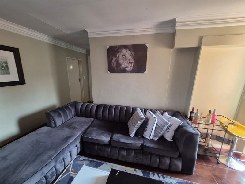 A living room area featuring crown molding, tiled flooring, and neutral wall tones, providing a comfortable space for relaxation.