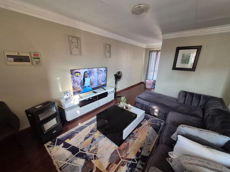 A comfortable living room featuring dark wood-look flooring, crown molding, and a wall-mounted electrical distribution board.