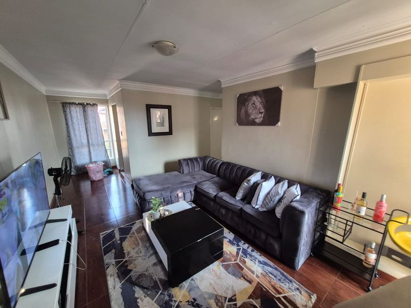 A comfortable living room featuring tiled flooring, crown molding, and a spacious layout suitable for relaxation.