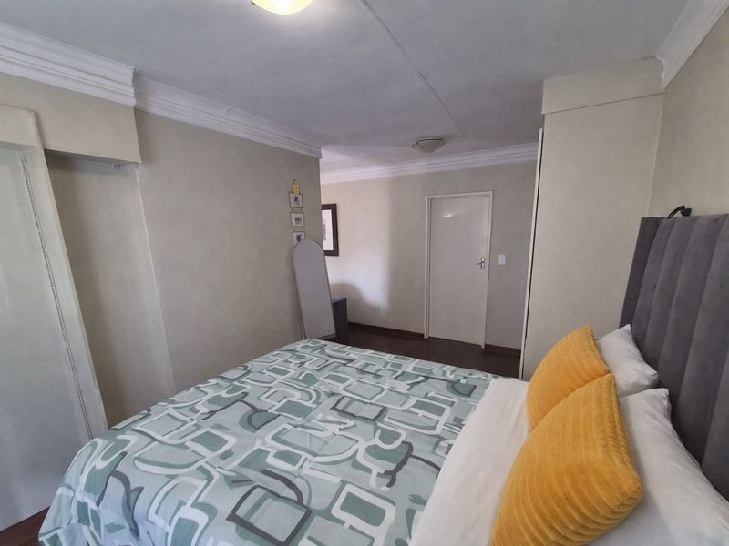 A bedroom featuring built-in cupboards, crown molding, and wooden flooring, providing a functional and comfortable living space.