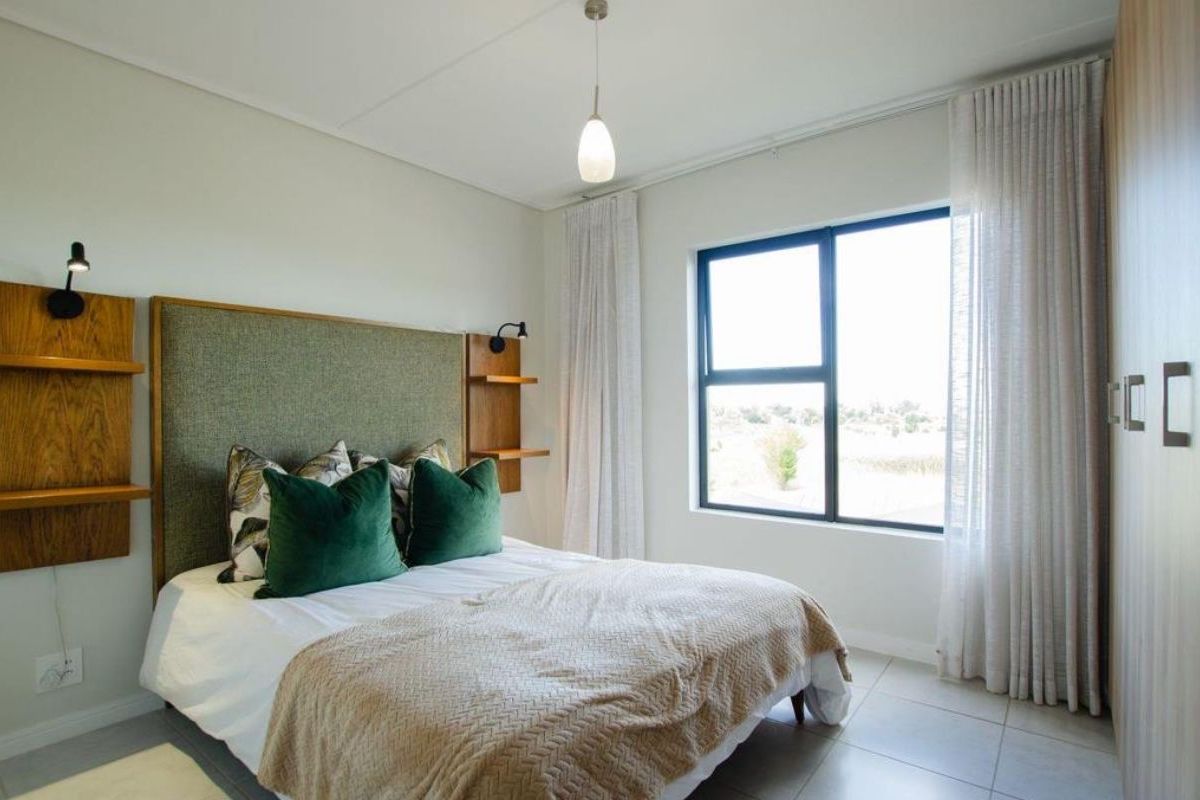 A well-maintained bedroom featuring tiled flooring, a built-in wardrobe, and large aluminium-framed windows that provide natural light.