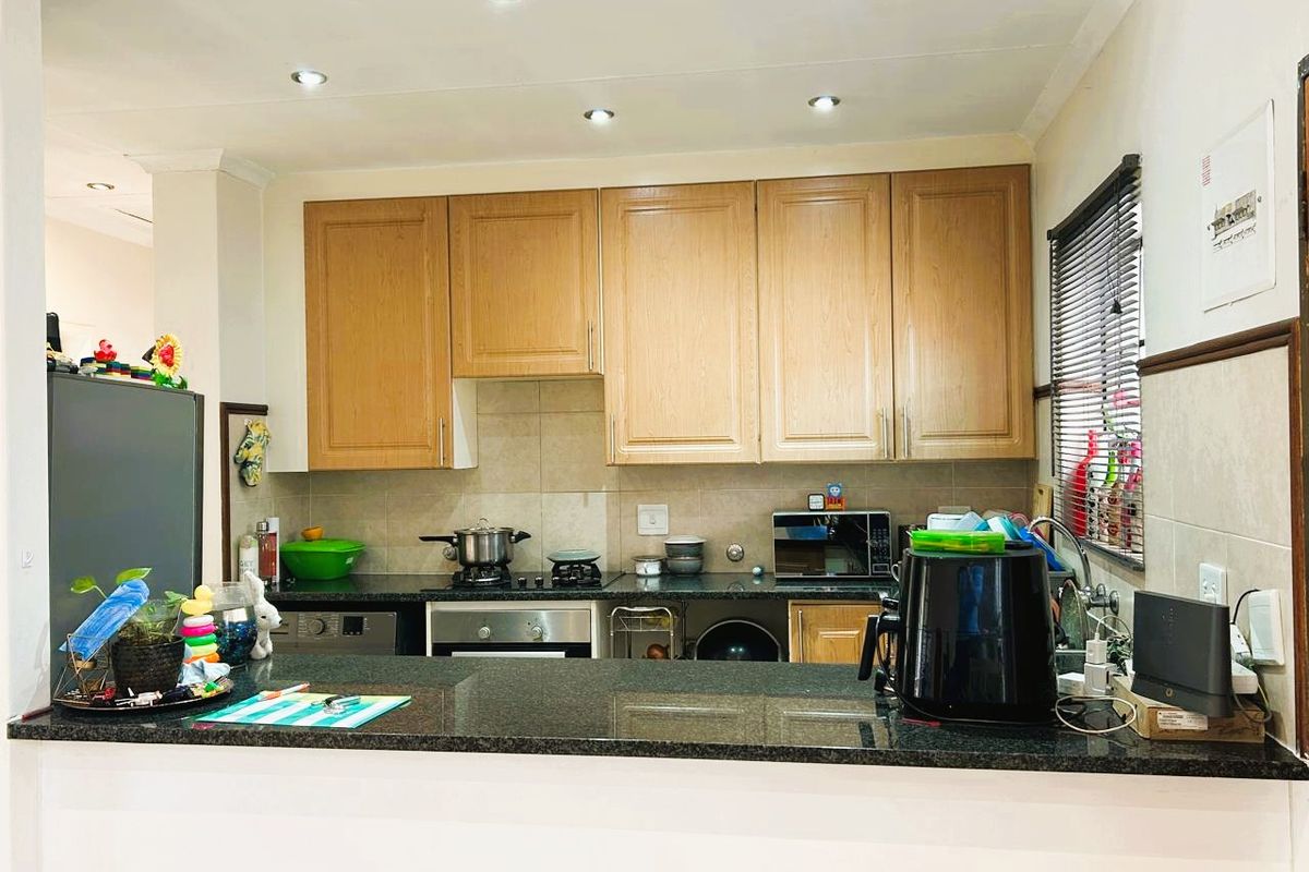 A functional kitchen featuring wooden cabinetry, granite countertops, a built-in oven, and a tiled backsplash with a breakfast bar counter.