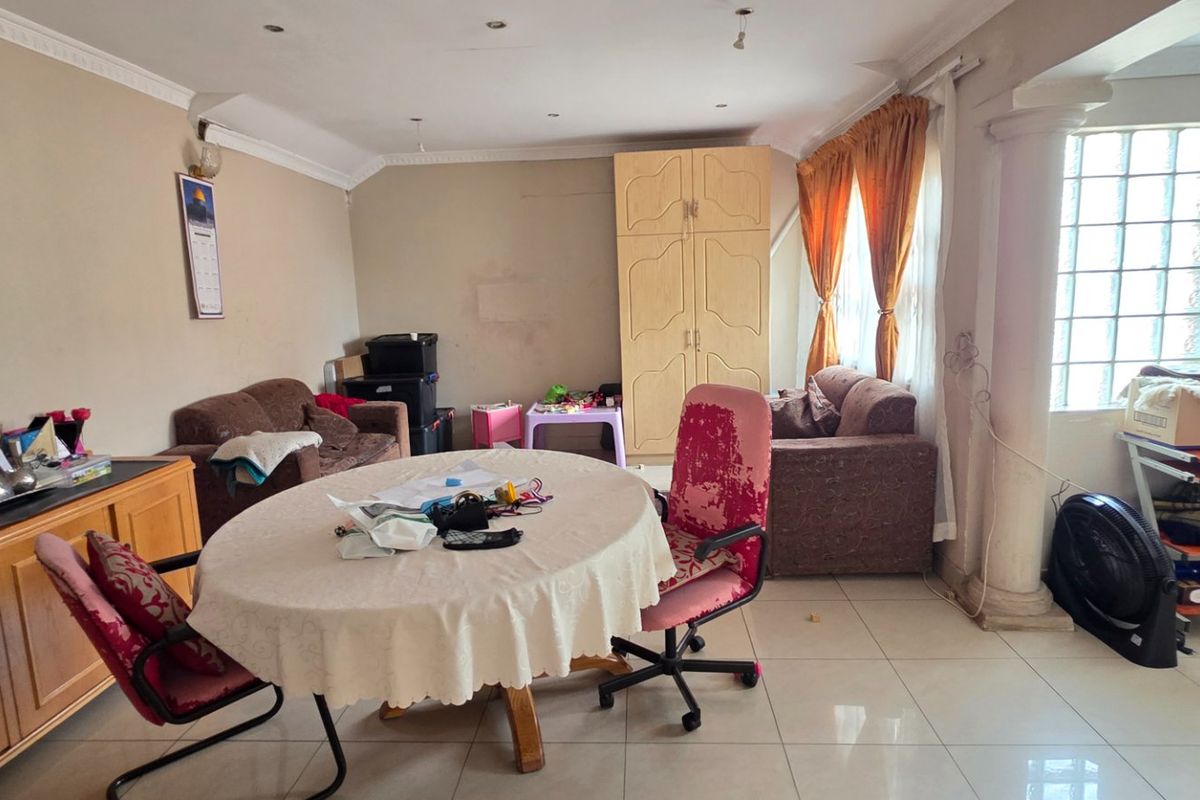 Spacious living area featuring tiled flooring, decorative columns, and a built-in wardrobe, offering a versatile layout for comfortable family living.