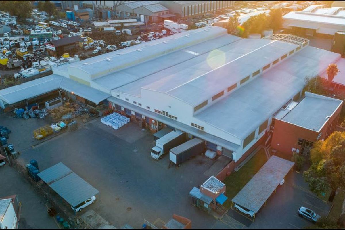 Aerial view of a large industrial warehouse facility featuring extensive yard space, loading bays, covered parking, and secure perimeter access.