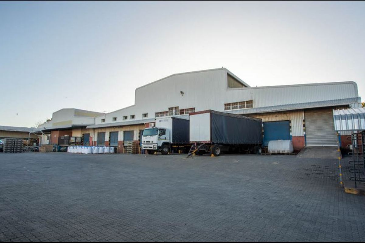 Industrial warehouse facility featuring multiple loading bays, roller shutter doors, and a spacious paved yard area suitable for logistics and heavy vehicle access.