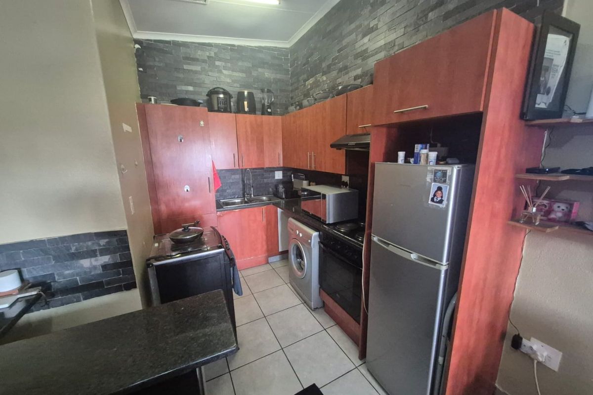 A functional kitchen featuring wood-tone cabinetry, stone tile backsplash, ceramic flooring, and integrated appliances, offering a practical layout for daily meal preparation.