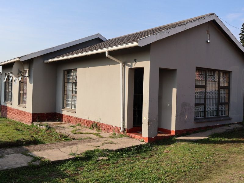 Front elevation of a single-story house featuring a tiled roof, security bars on windows, and a concrete walkway leading to the entrance.