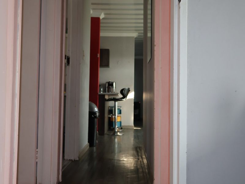 A view through a hallway leading into an open plan living and kitchen area with laminate flooring.