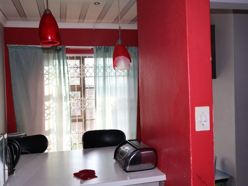 A kitchen area featuring a breakfast counter, pendant lighting, and a window with a security gate.