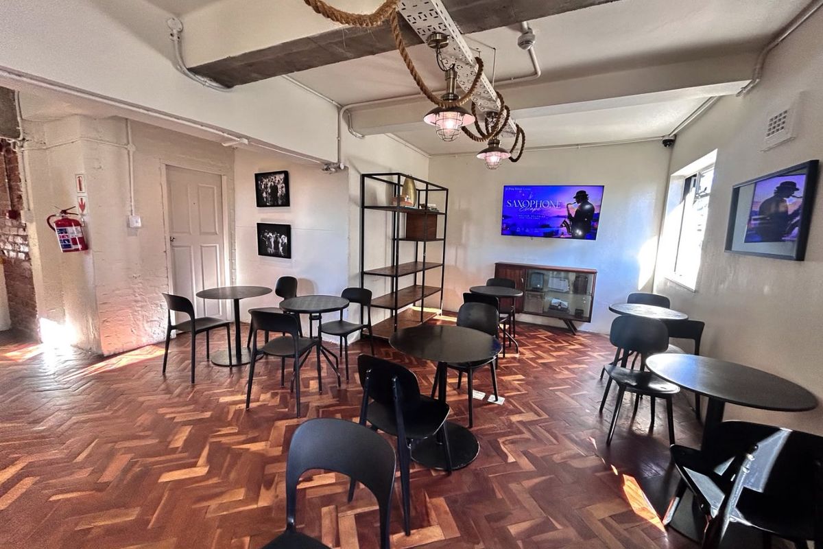 A spacious living area featuring classic herringbone parquet flooring, exposed ceiling beams, and industrial-style pendant lighting, creating a characterful and open atmosphere.