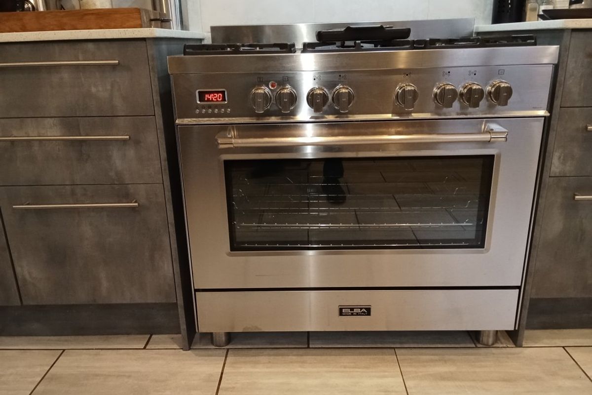 A modern kitchen featuring a stainless steel Elba gas stove and oven, complemented by grey cabinetry and stone countertops.