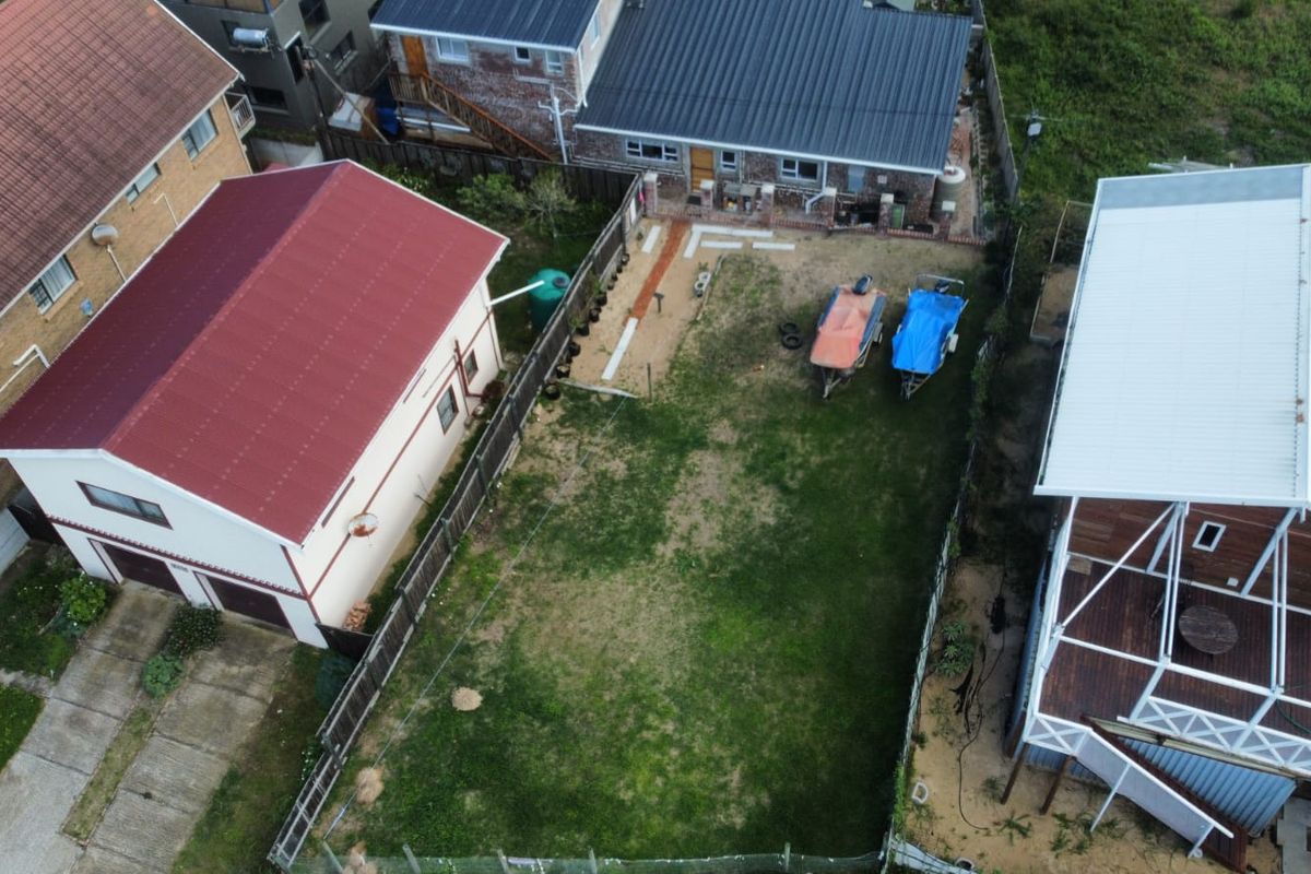 Aerial view of a residential plot featuring a grassed yard, perimeter fencing, and a water tank, situated between neighboring properties.