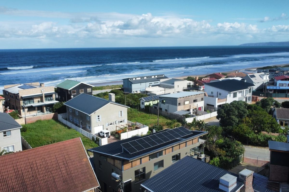 An elevated aerial view of a coastal residential neighborhood, showcasing the proximity to the ocean and surrounding properties.
